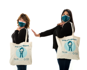 Two women wearing NRAS tote bags standing at a distance in front of each other